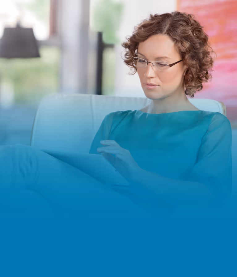 A woman sitting on a couch looking at her cell phone