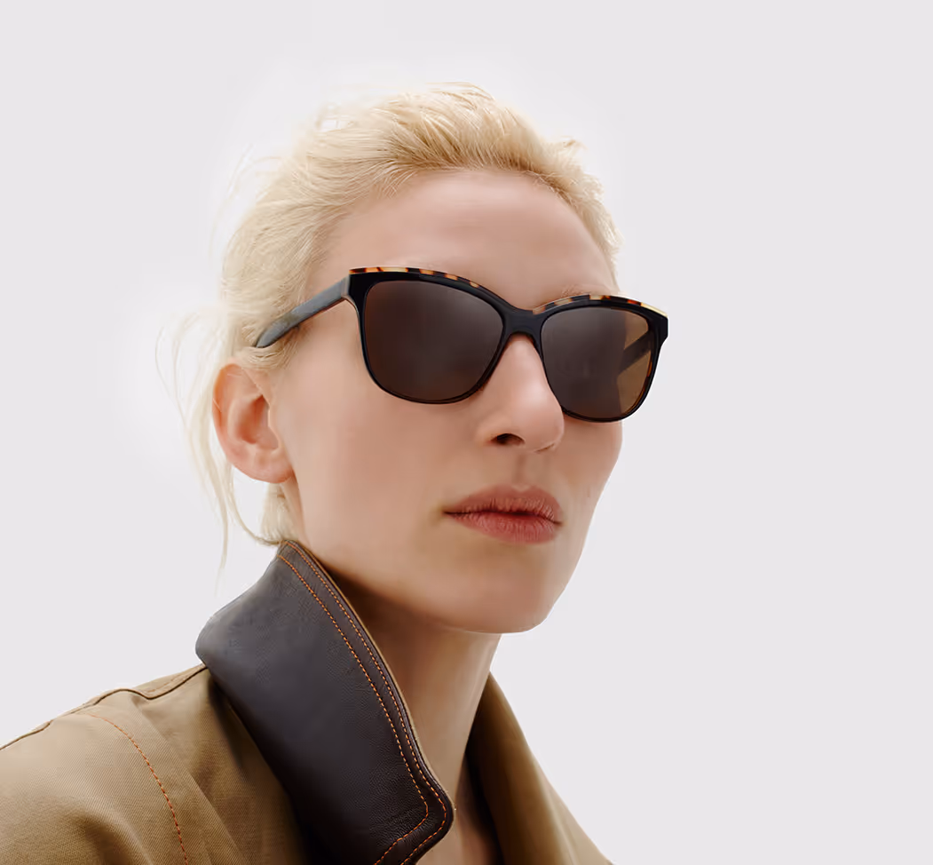 A woman wearing sunglasses and a trench coat