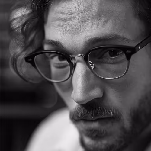 A black and white photo of a man wearing moscot glasses