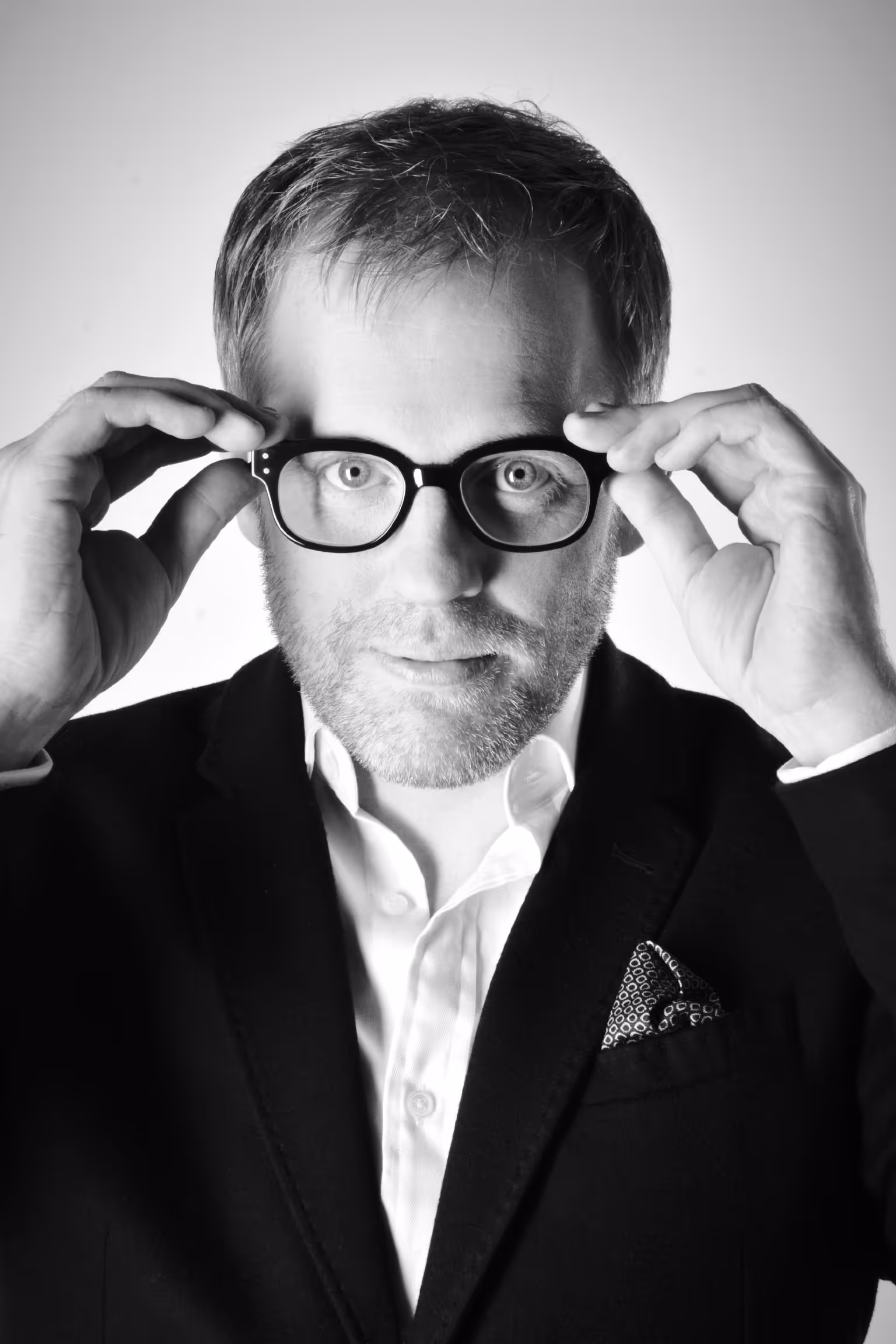 A man in a suit and glasses poses for a picture