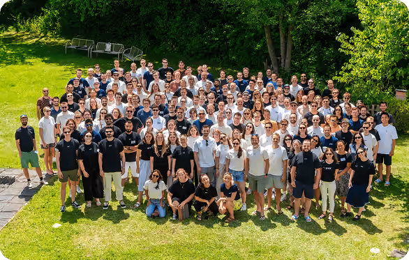 Big group of people (the gridX team) standing in a park looking at the camera