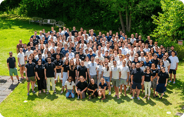 Big group of people (the gridX team) standing in a park looking at the camera