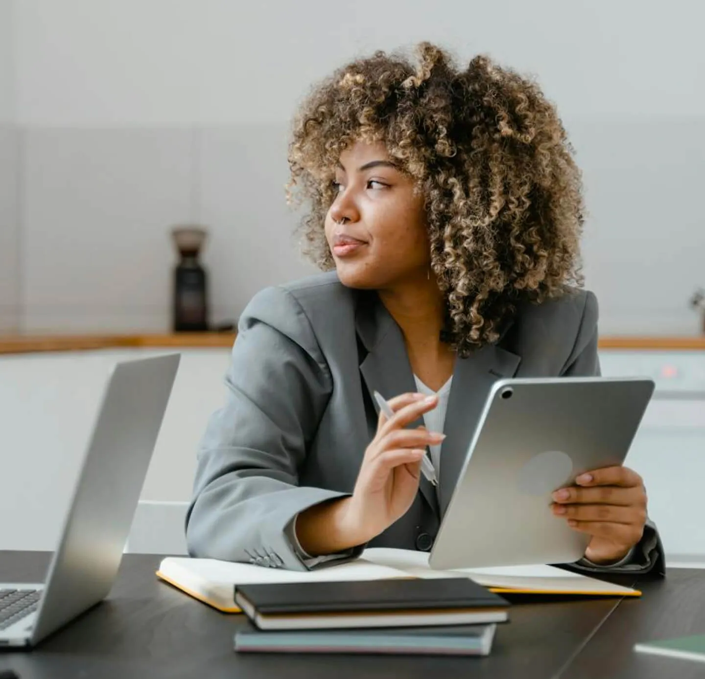 african american woman looking out the window while holding a tablet