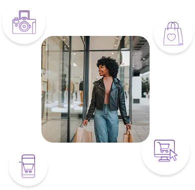Smiling woman in leather jacket carrying paper shopping bags outside store with glass windows.
