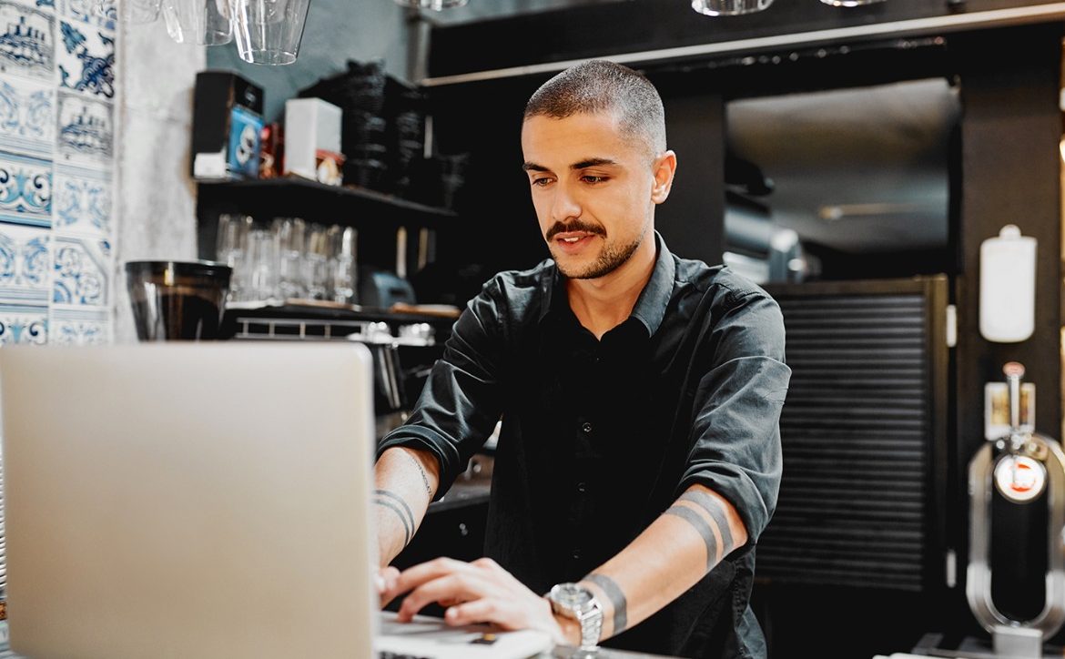 shot of a male restaurant owner using a lapatop inside of his cafe