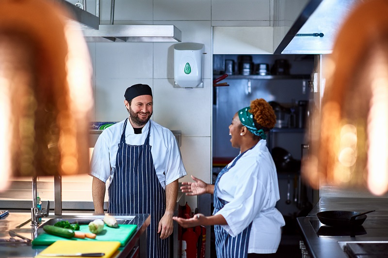 Male and female colleagues working in restaurant, relaxing and chatting
