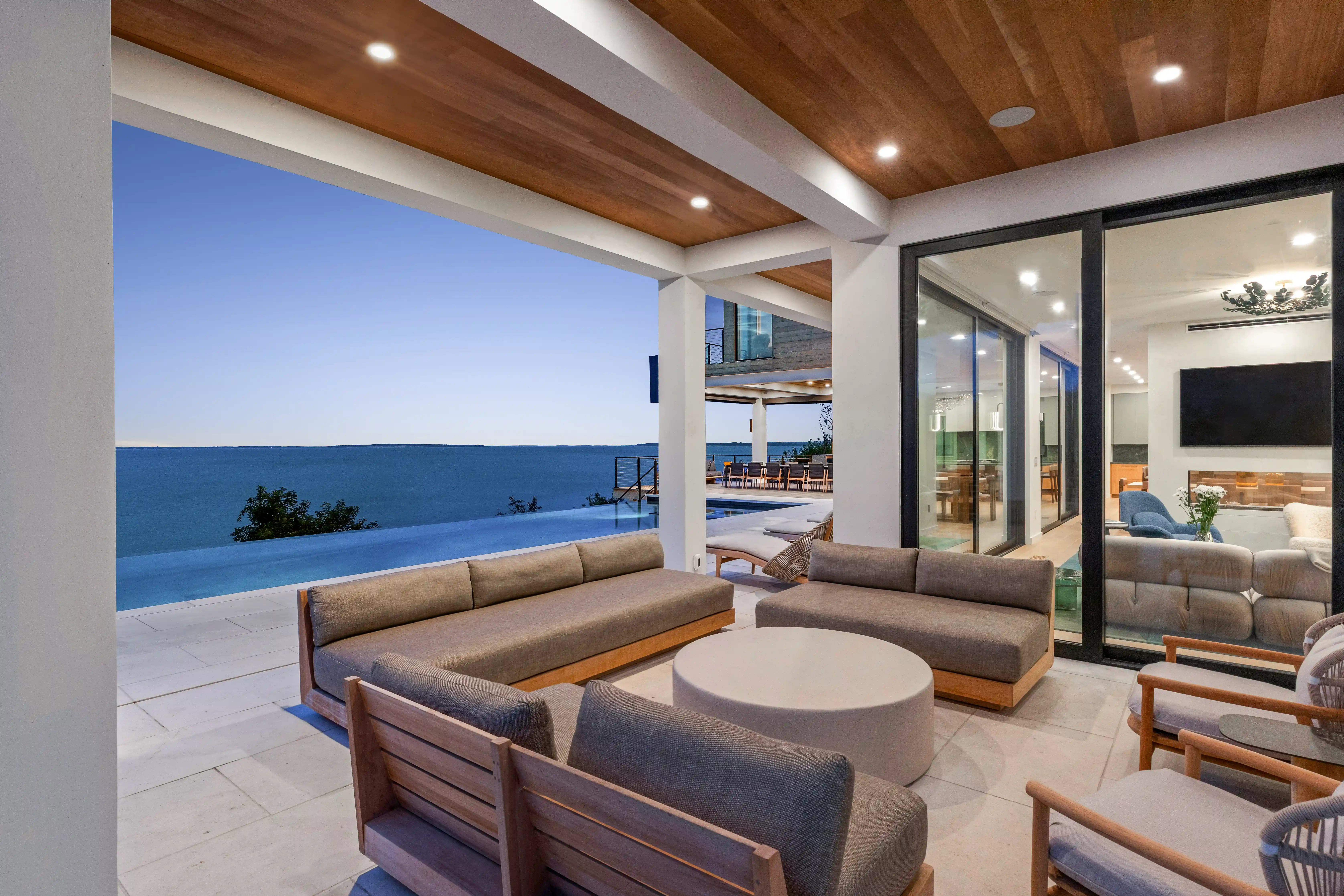 Luxury waterfront outdoor lounge area with infinity pool and modern custom home