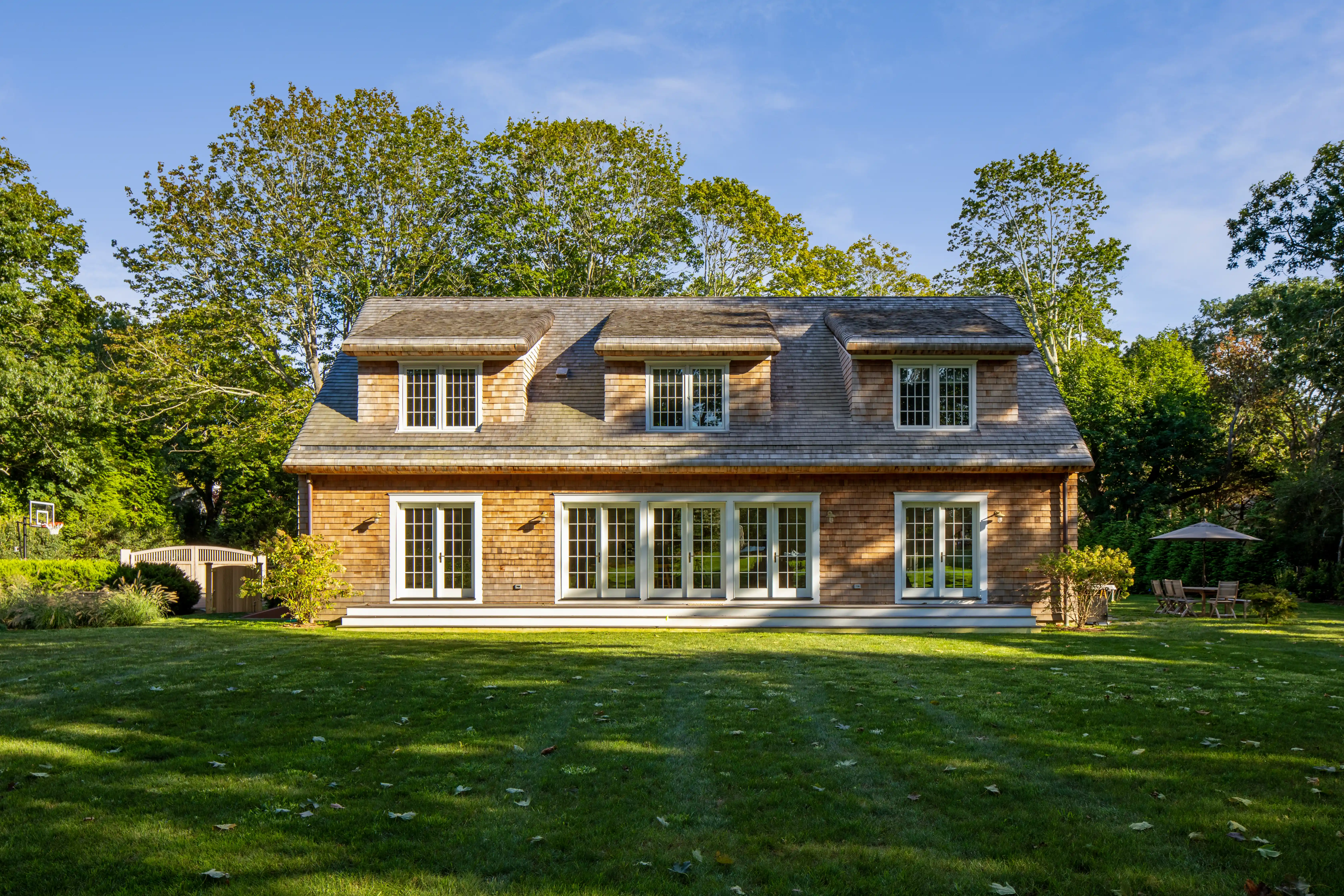 Luxury custom home exterior with cedar siding and landscaped lawn