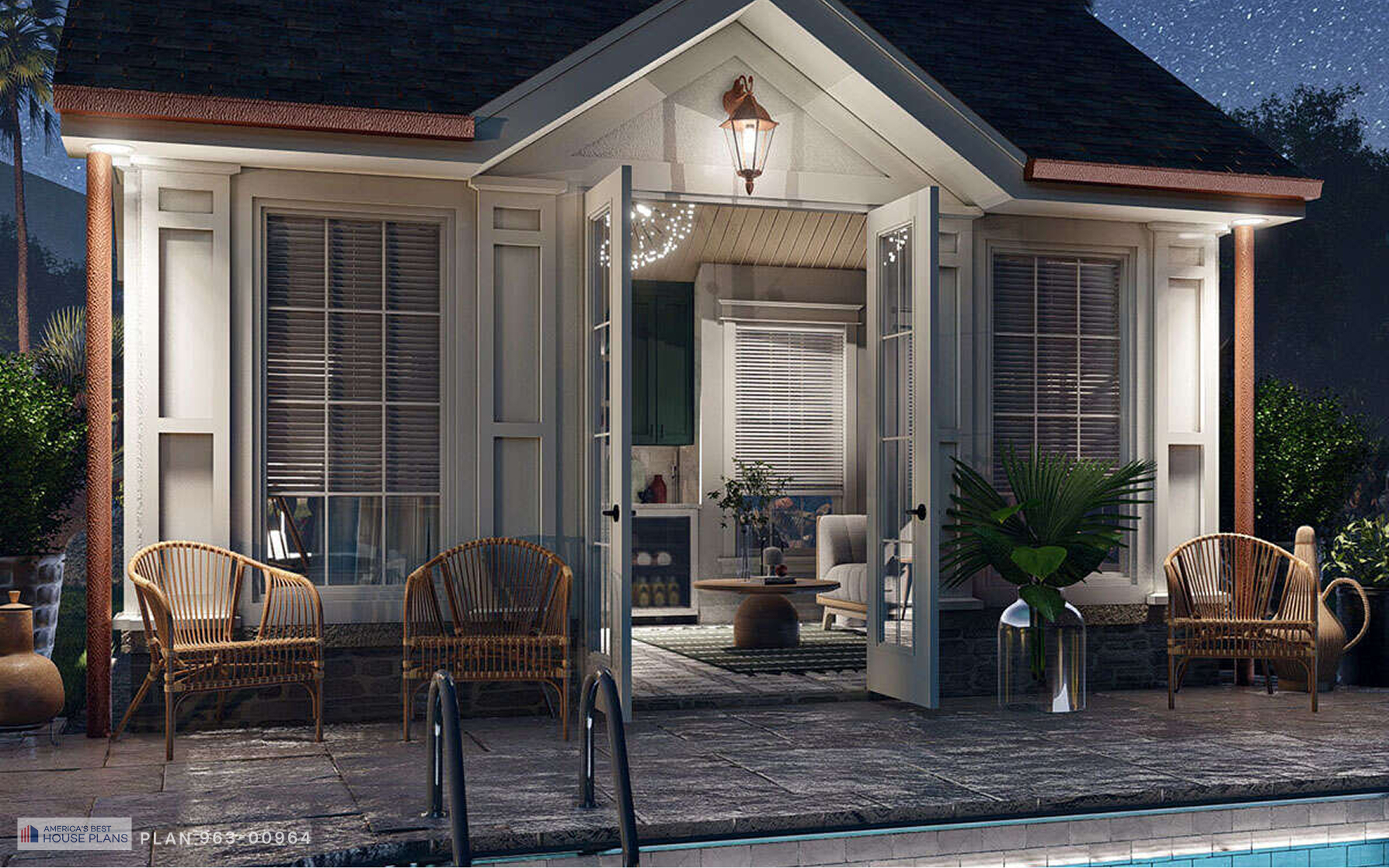 Illuminated cottage-style pool house at night with open French doors