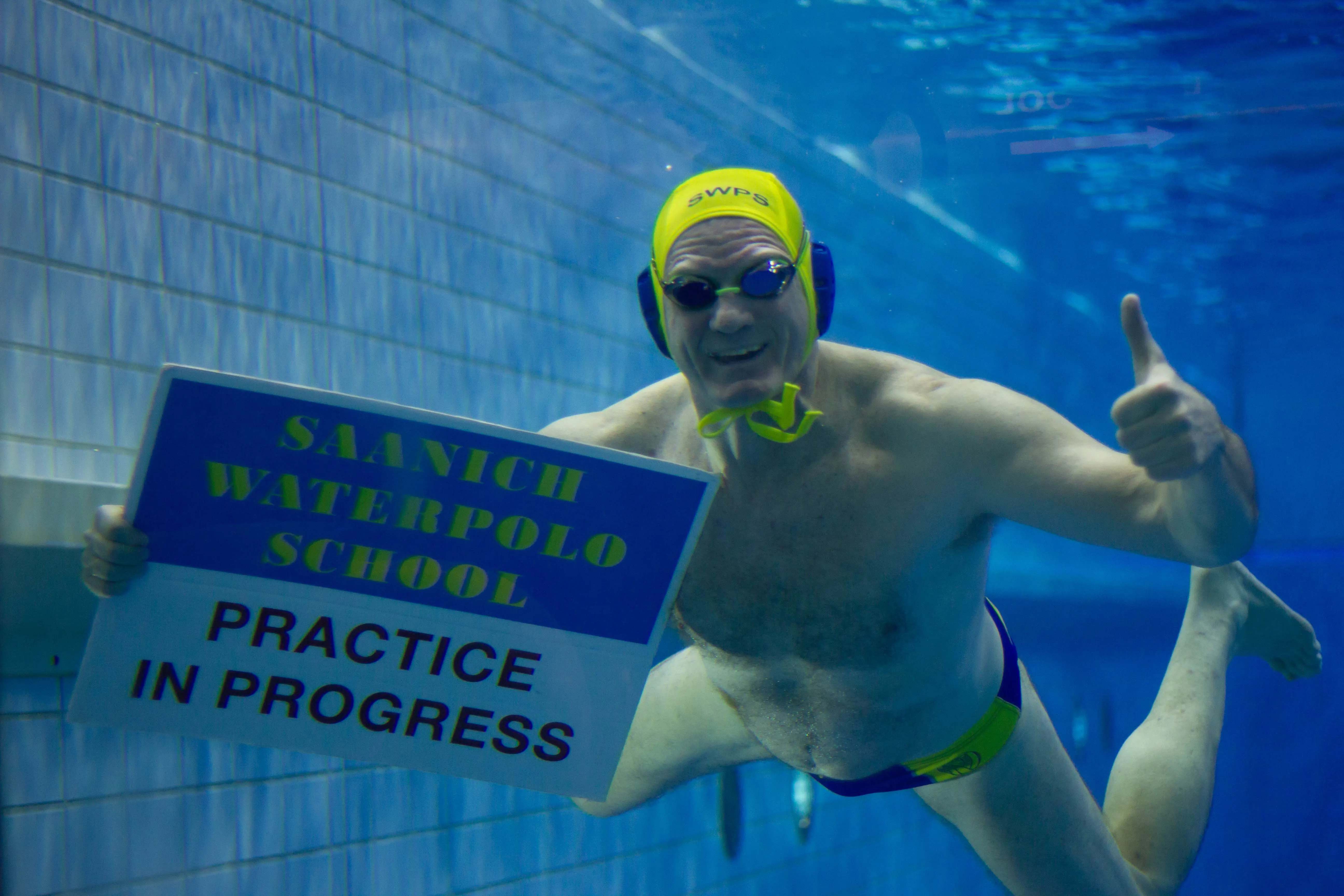 Swimmer under water holding a Practice in Progress sign