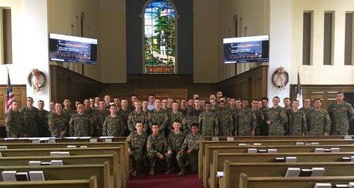Group of military personnel in camouflage uniforms posing inside a church with Chris D. Connors.