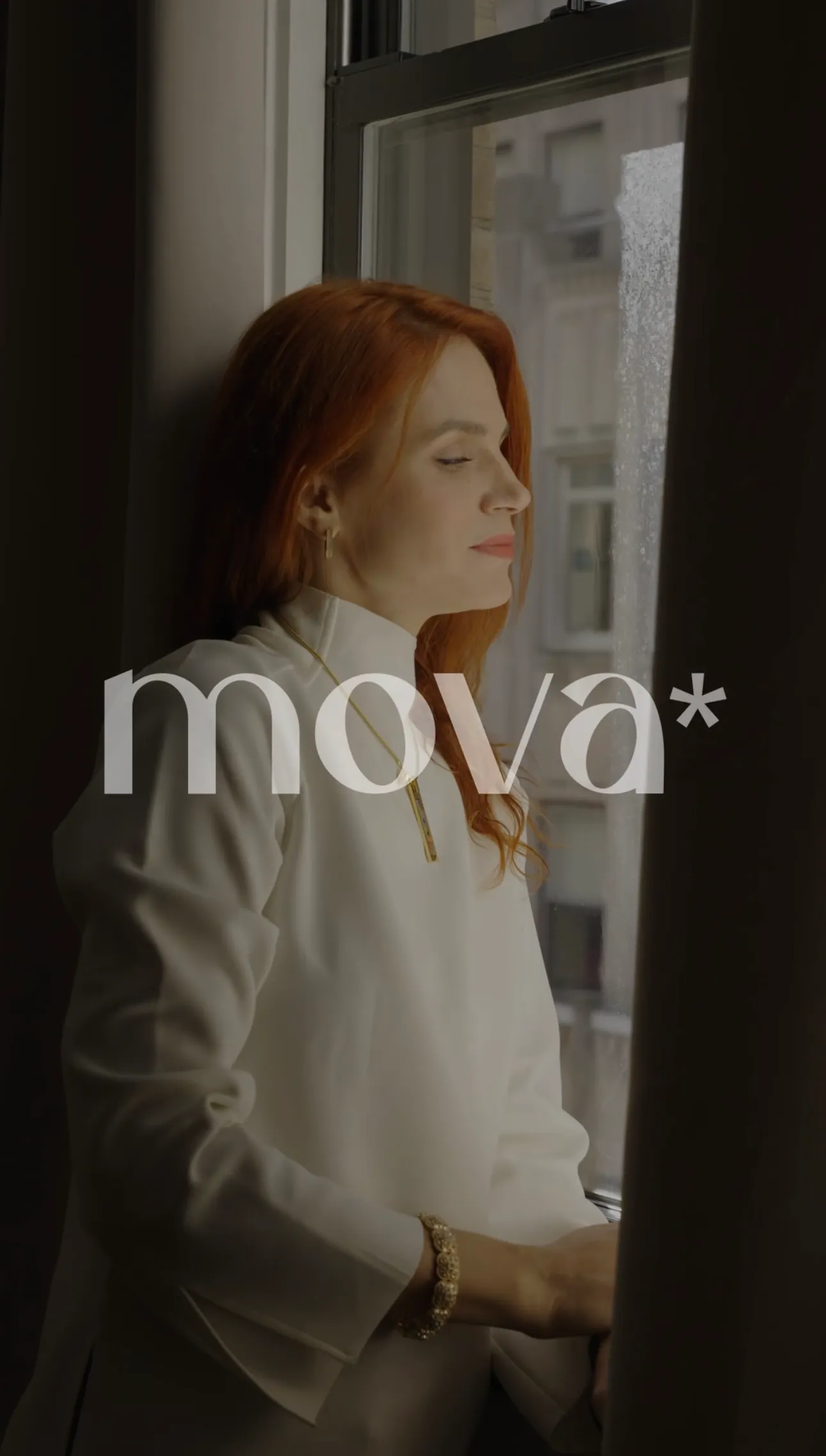 Woman in a white blazer by a window in a branded video for Mova