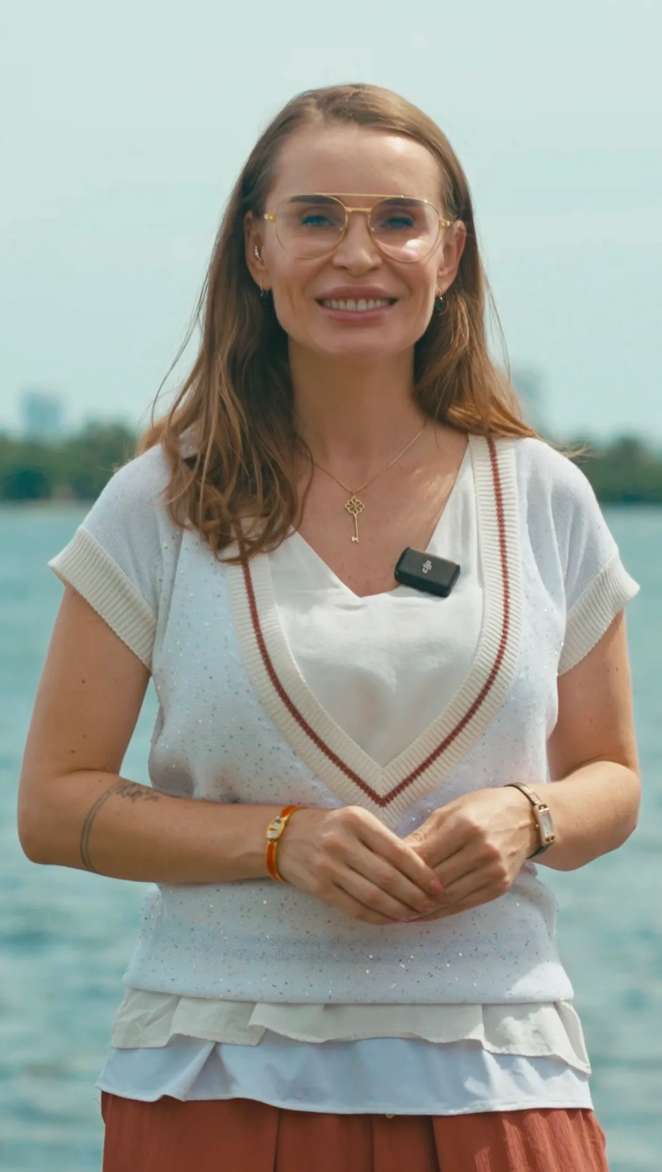 Woman with a lapel mic speaking on camera by the water in Miami
