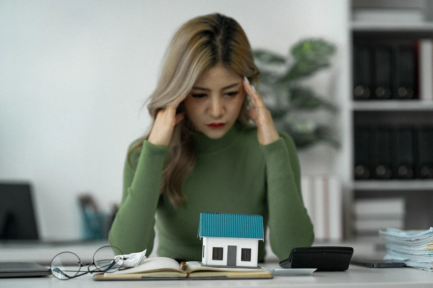 Frau mit Rechner und Haus auf dem Schreibtisch