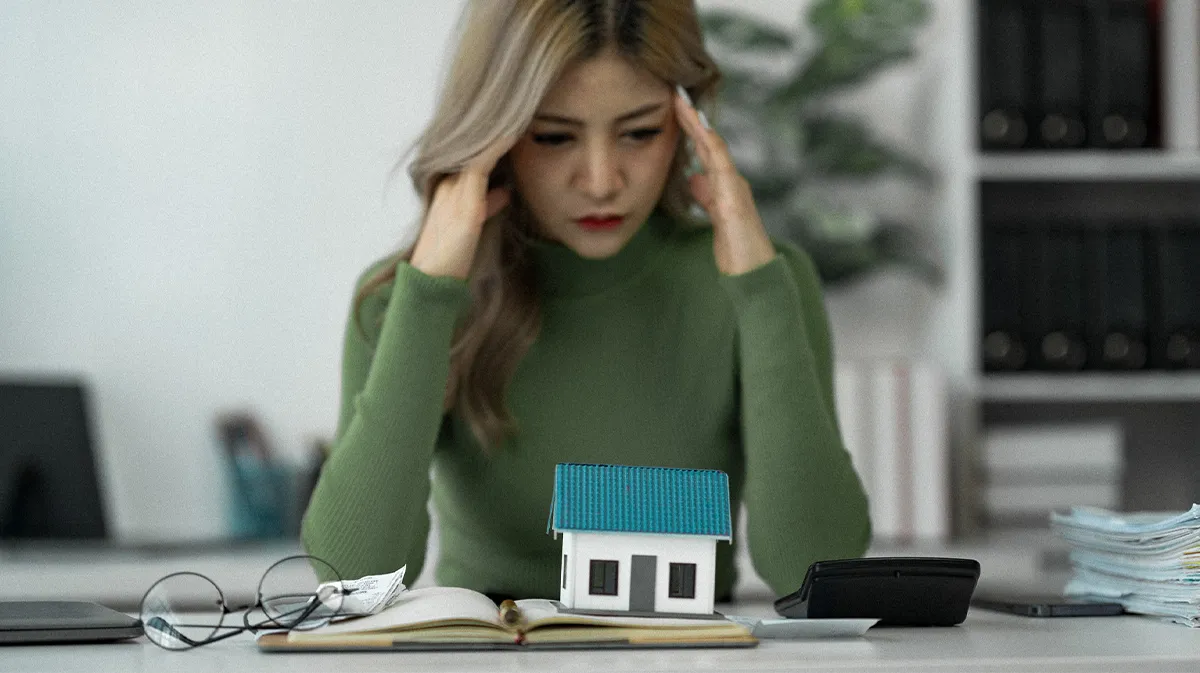 Frau mit Rechner und Haus auf dem Schreibtisch