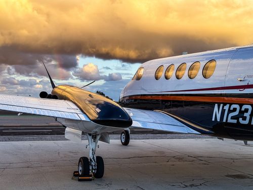 A black SUV parked beside a small plane on the tarmac.