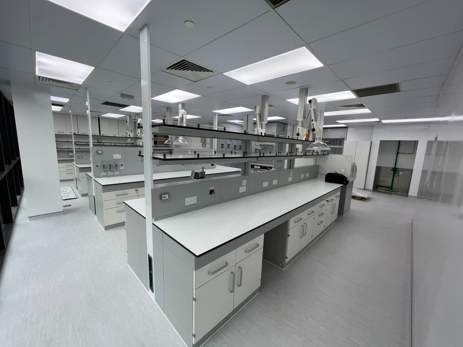 A modern and well-equipped laboratory with multiple white lab benches and grey cabinetry