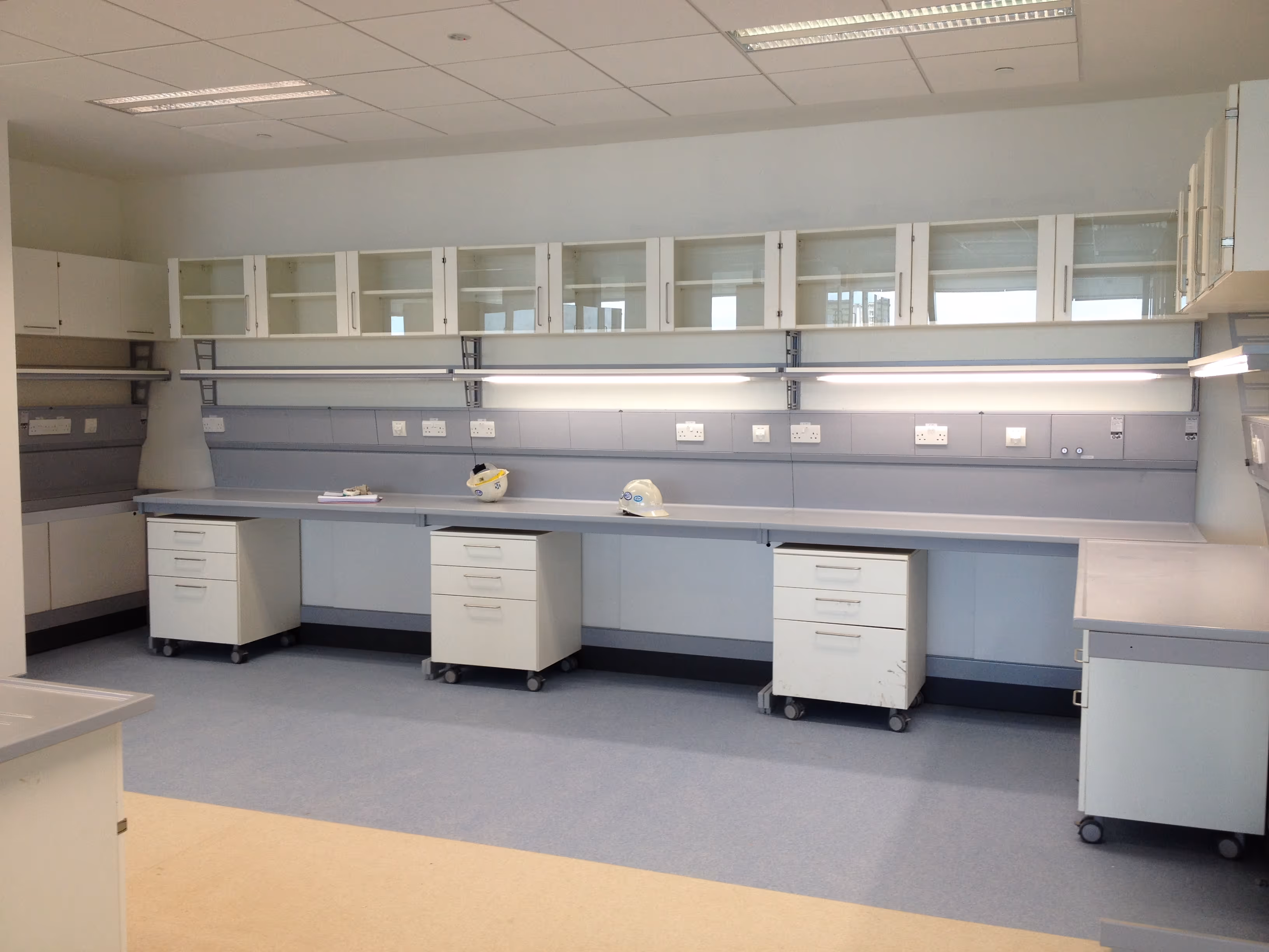 Empty modern laboratory with white cabinets, shelves, and workbenches