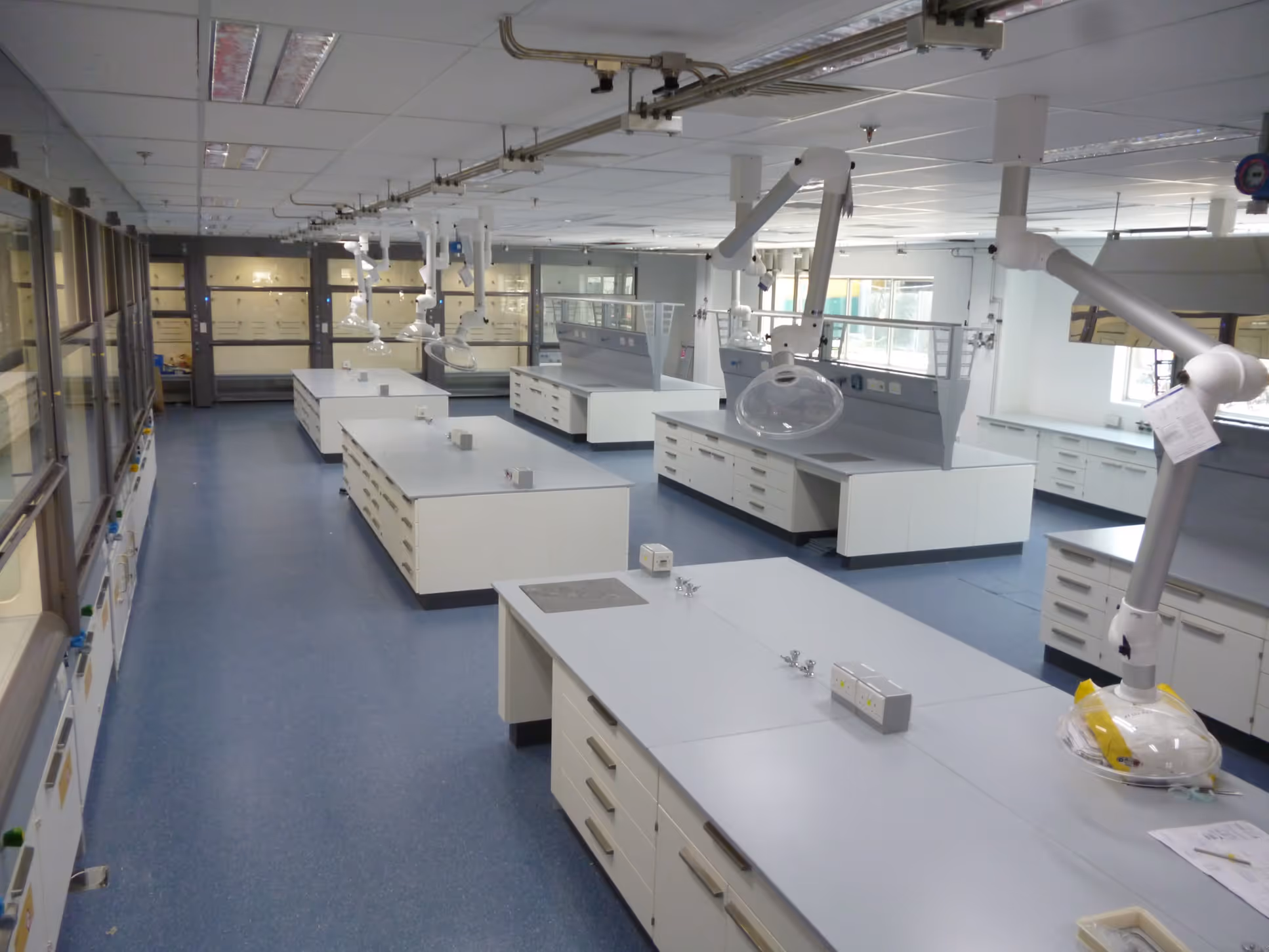 Modern, empty scientific laboratory with white workstations and blue flooring
