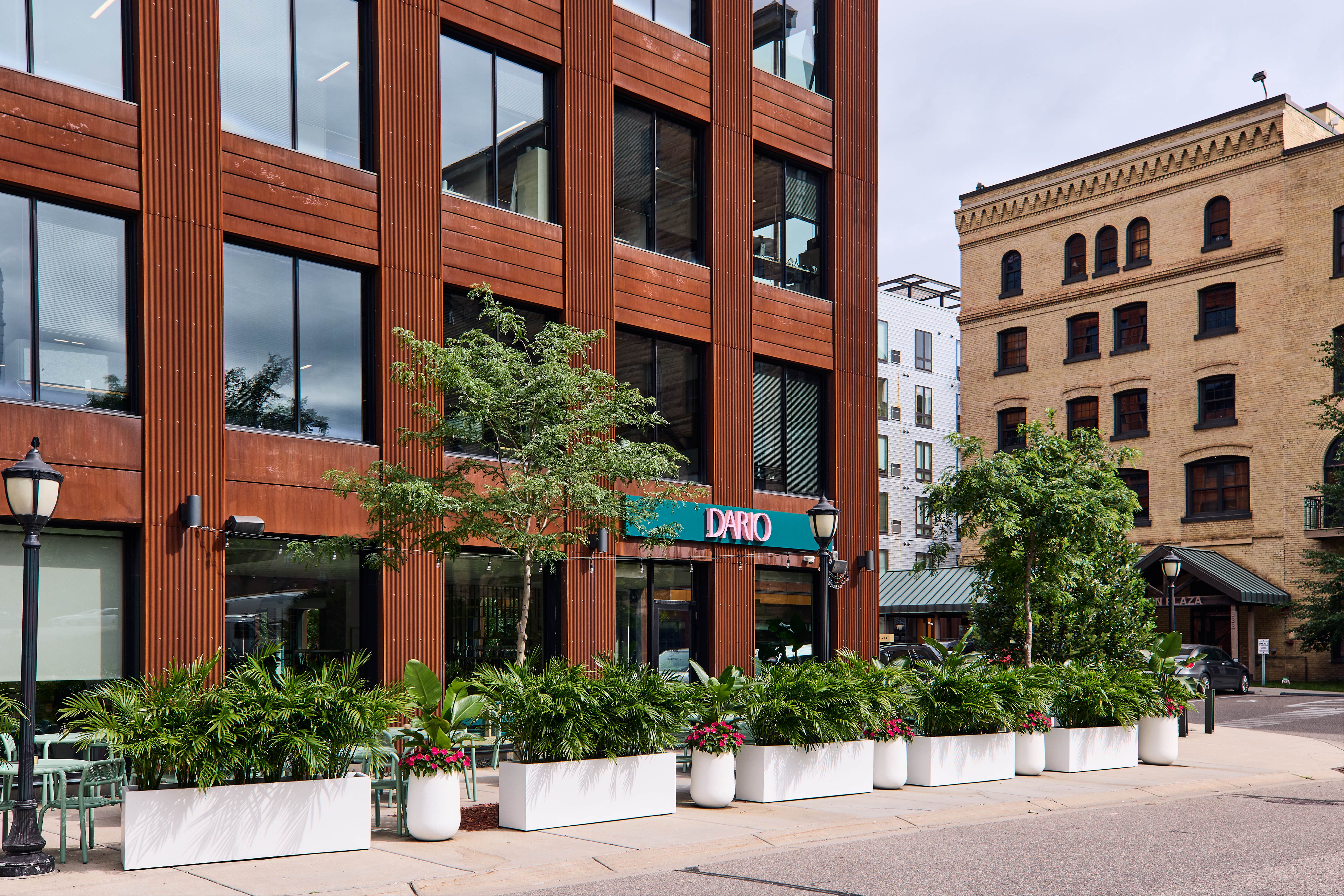 Exterior of Dario restaurant with modern building and lush sidewalk planters