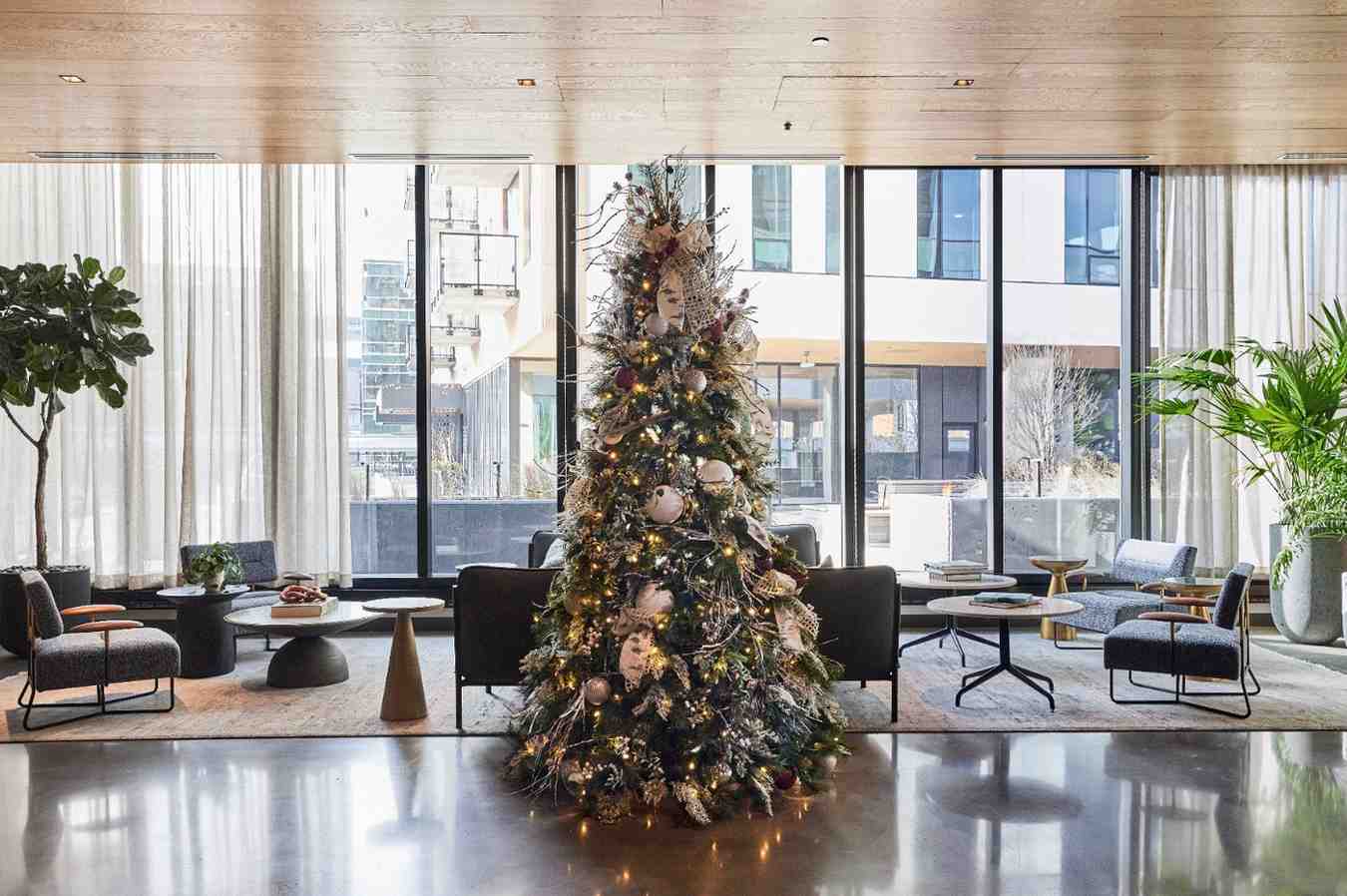 Decorated Christmas tree in a modern lobby with lounge seating.