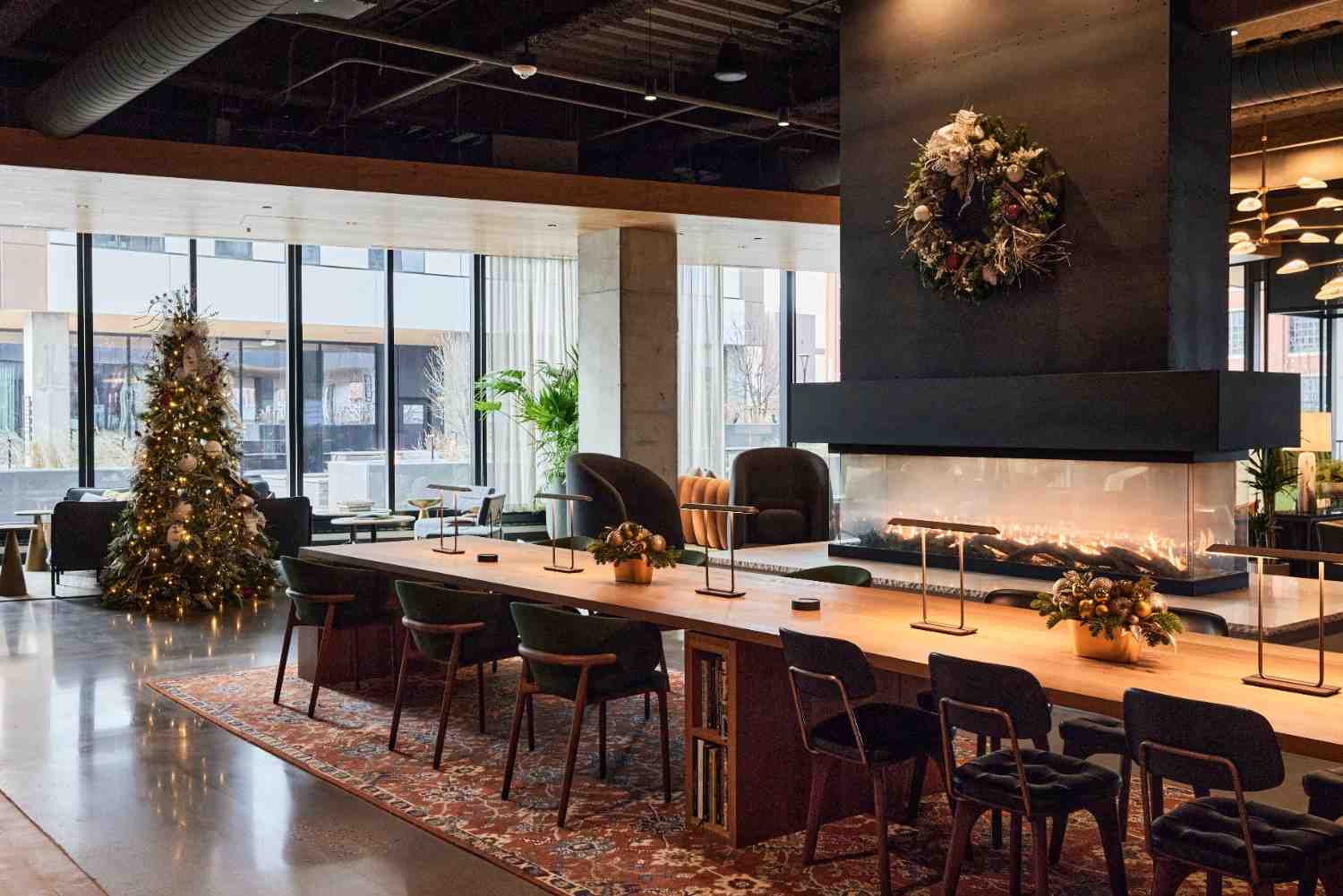 Lobby decorated for the holidays with a Christmas tree, wreath, and fireplace seating.