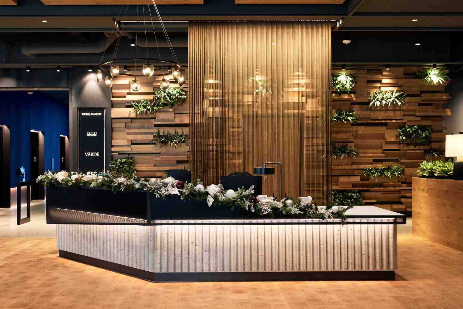 Reception desk decorated with holiday garland in a modern lobby with wood accents