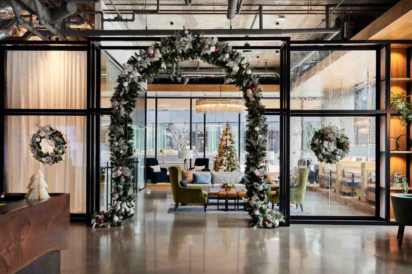 Lobby entrance decorated with holiday garland arch, wreaths, and a Christmas tree.