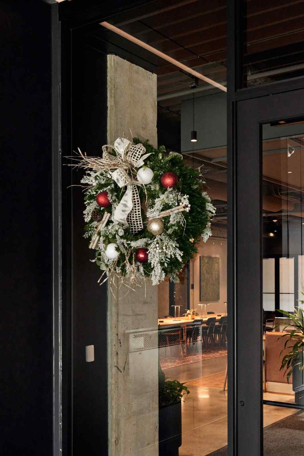 Holiday wreath with red, white, and gold ornaments hanging in a modern lobby