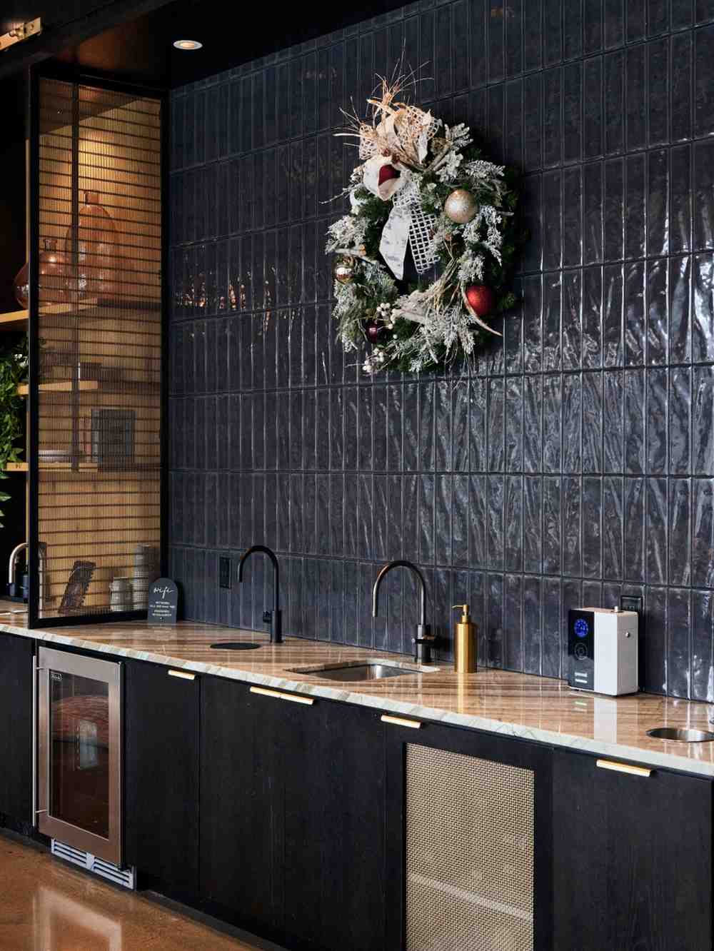 Holiday wreath with ornaments hanging above a modern kitchenette.