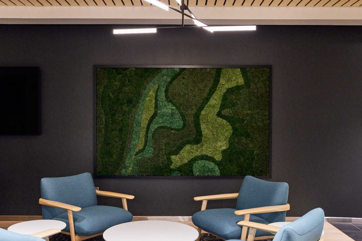 Framed green moss wall art in modern office lounge.