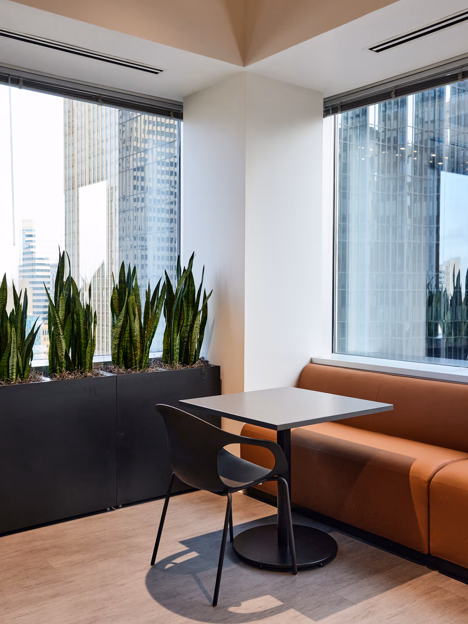 Black planters with snake plants beside small office table and chair.