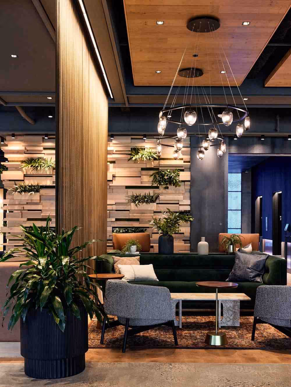 iophilic hotel lounge with lush indoor plants, wood feature wall, and modern seating arrangement.