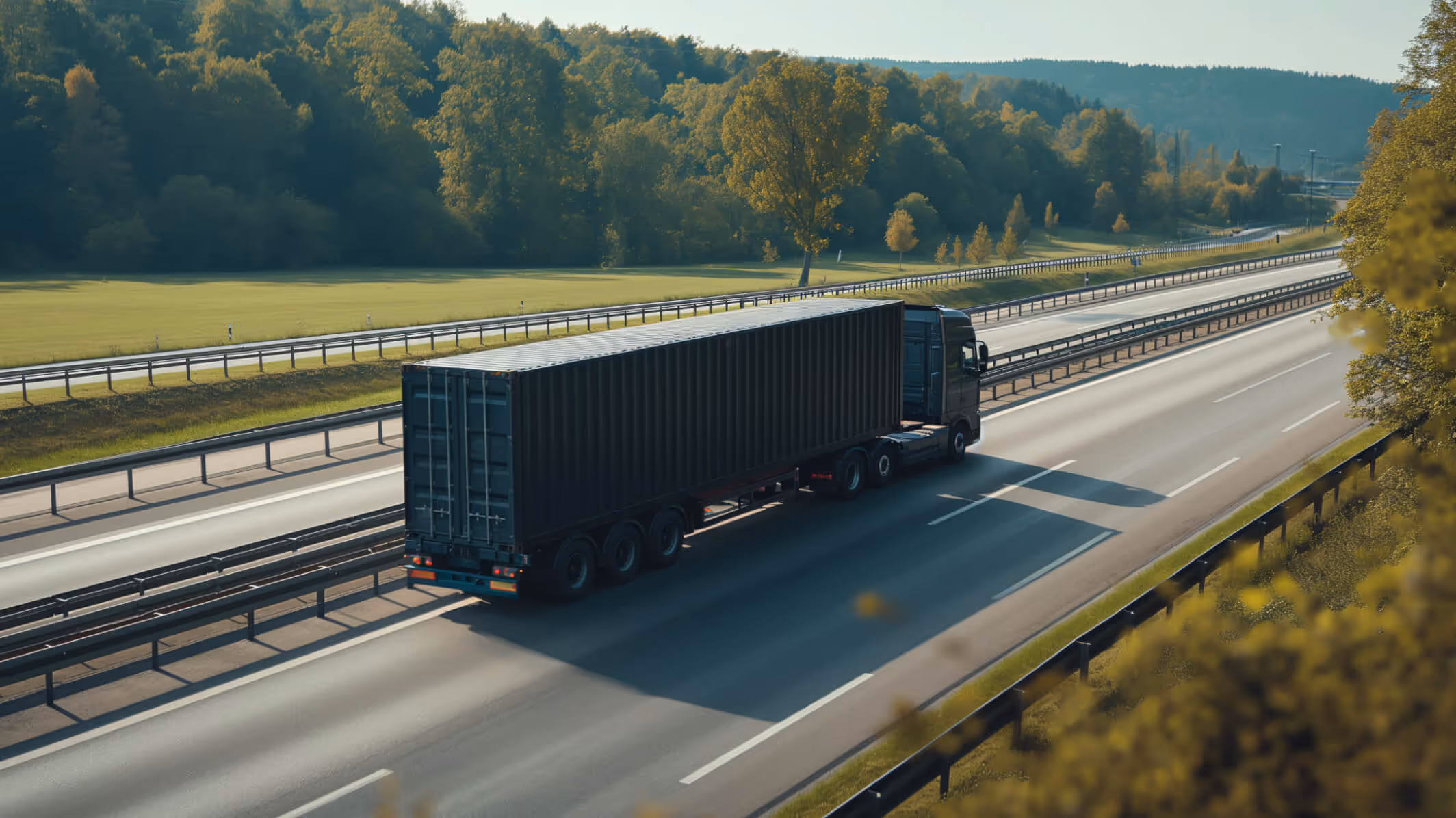 A large semi-truck hauling a shipping container on a multi-lane highway. Kraftblock's mobile storage allows you to connect heating sources located far away to applications.