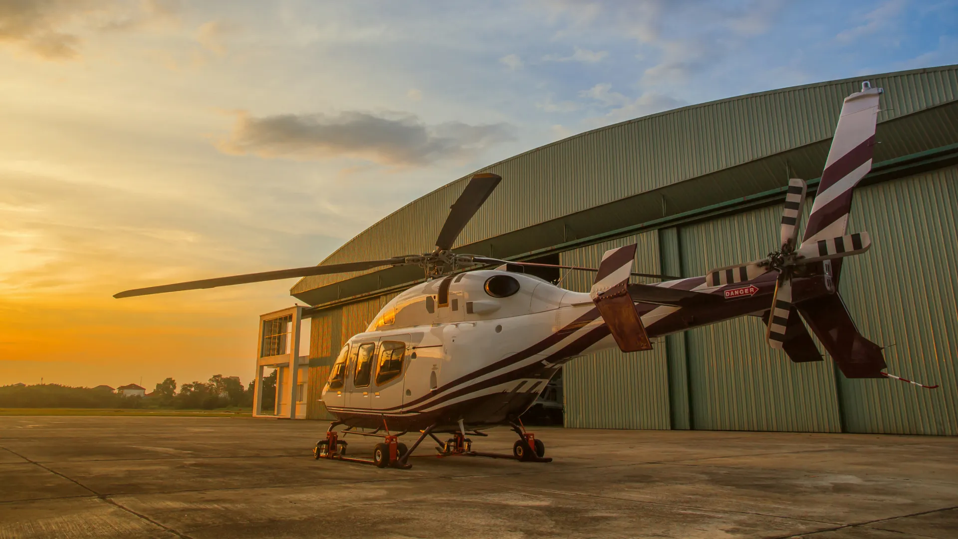A helicopter parked in front of a hangar.