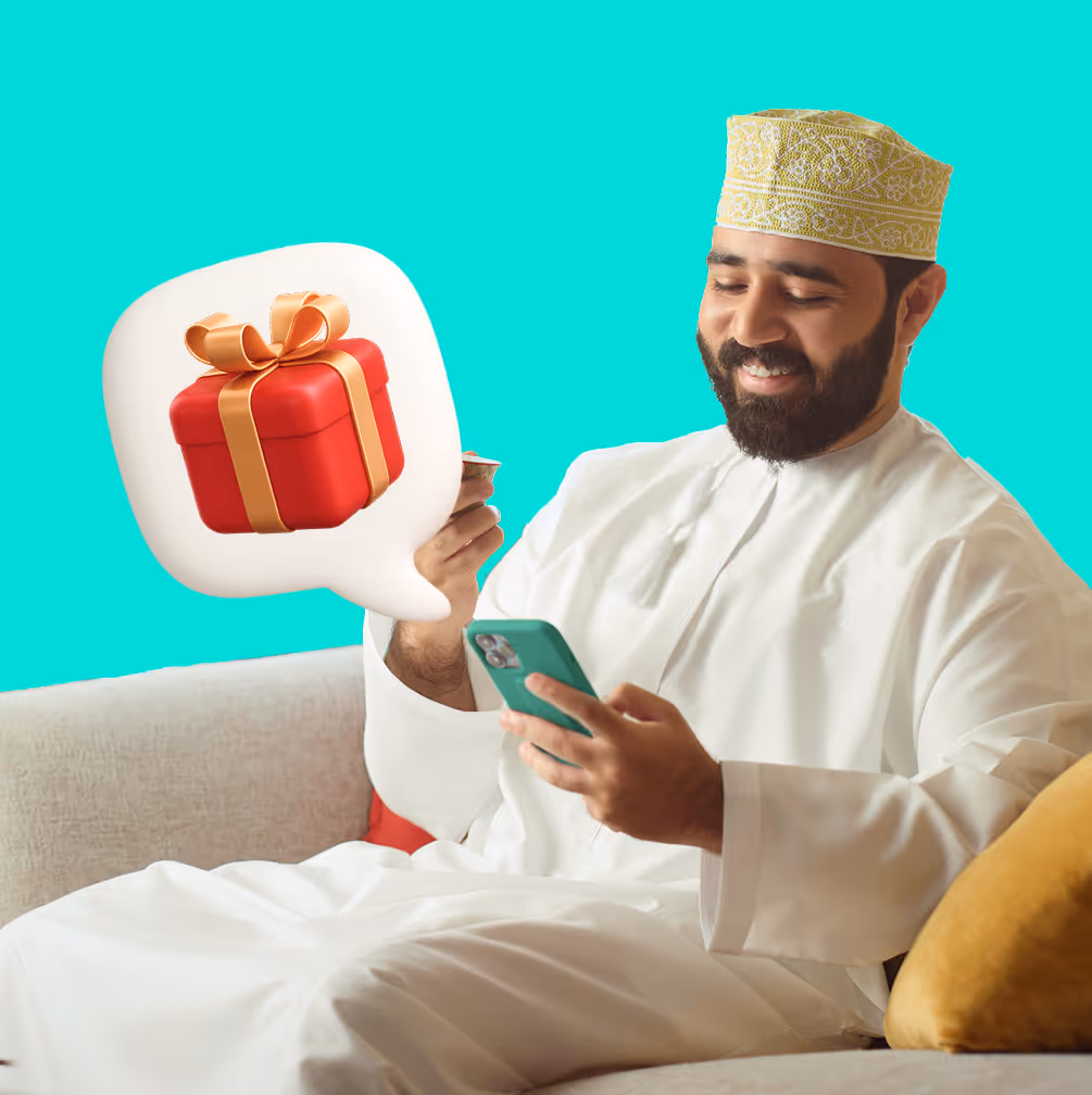 Smiling man in traditional Middle Eastern clothing looking at his smartphone with a gift box icon in a speech bubble nearby.
