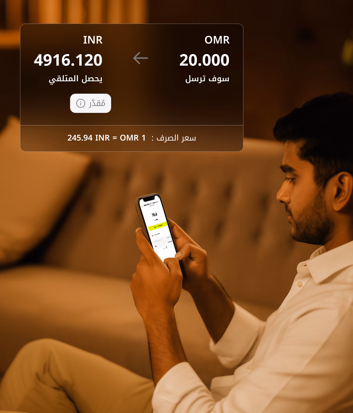 يظهر رجل يرتدي قميصًا أبيض يجلس على الأريكة مستخدمًا الهاتف مع تحويل العملات من 20 ريال عماني إلى 4916.120 روبية هندية.