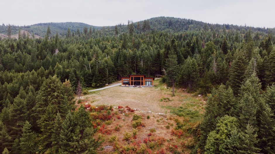 Aerial view of a modern cabin surrounded by lush forest in Priest River, Idaho.
