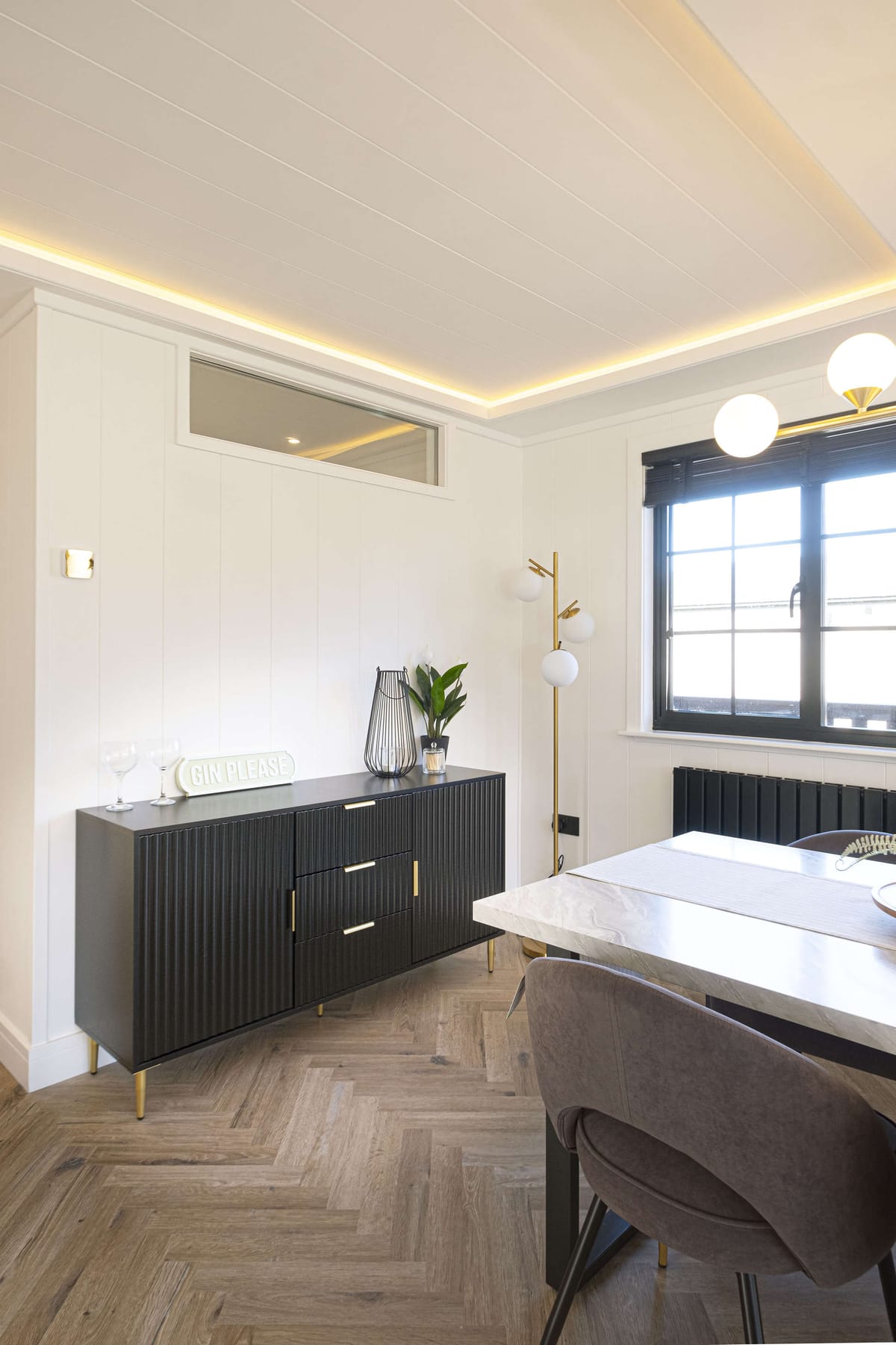 Modern Dining Room with Black Sideboard, Elegant Lighting, and Herringbone Wood Flooring