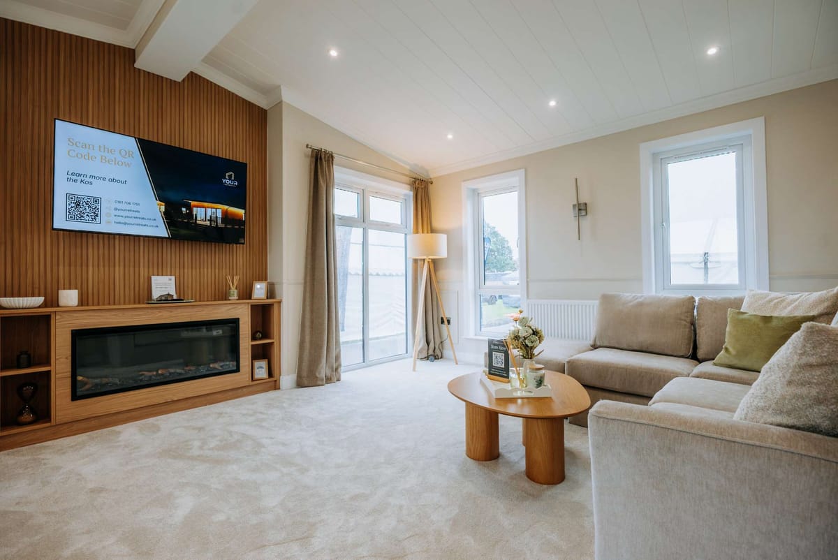 Modern Living Room with Elegant Beige Sofa, Wooden Fireplace and TV on Textured Accent Wall, Large Windows with Natural Light, and Minimalist Decor