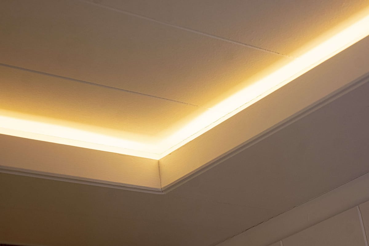 Warm Ambient LED Strip Lighting on Ceiling with Subtle Architectural Details in Cozy Interior Setting