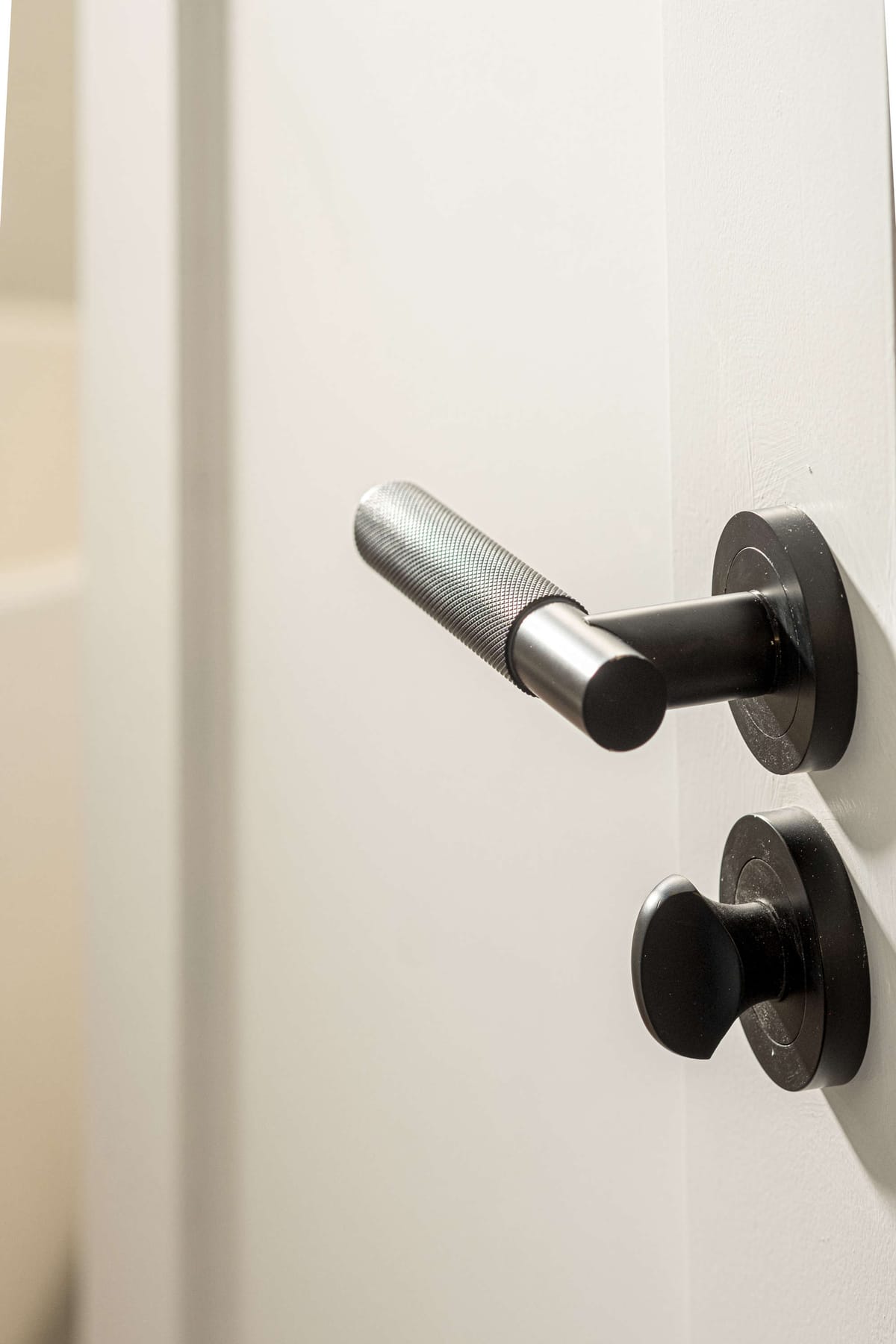 Close-Up of Modern Metallic Door Handle with Textured Grip on White Door Surface