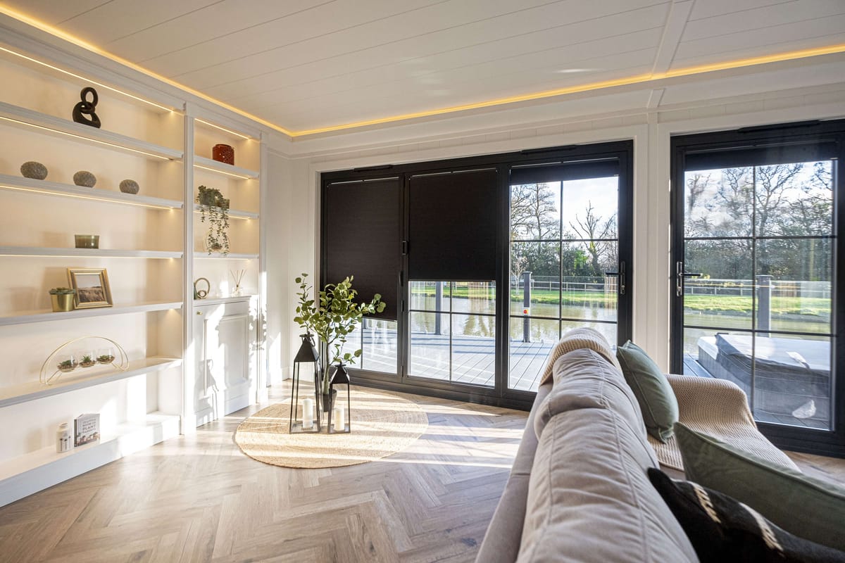 Modern Living Room with Large Glass Doors Overlooking Scenic Pond and Minimalist Shelving Decor in Natural Light