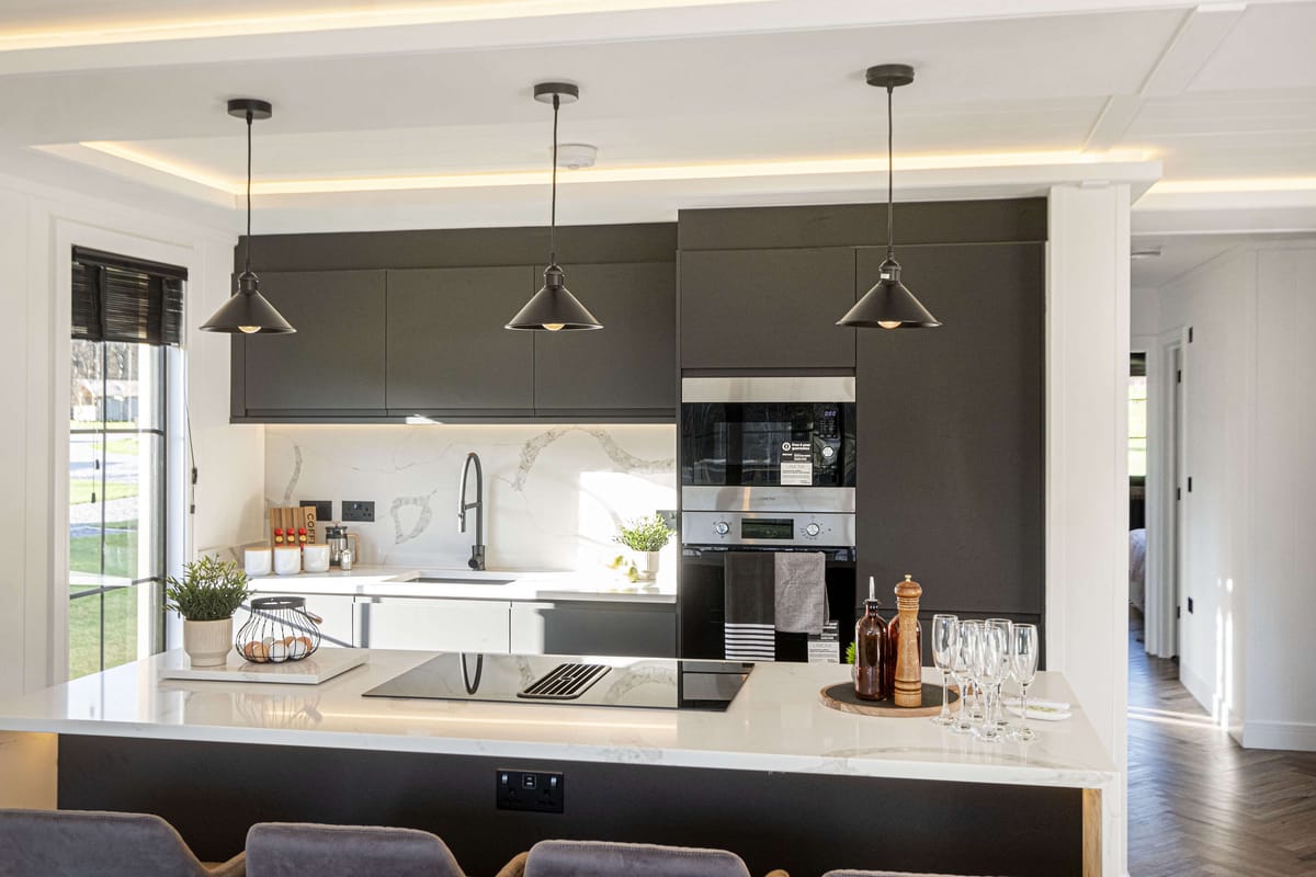 Modern Kitchen Interior with Black Cabinets, Pendant Lighting, and Marble Countertops Featuring Built-In Appliances, Induction Cooktop, and Elegant Decor Accents