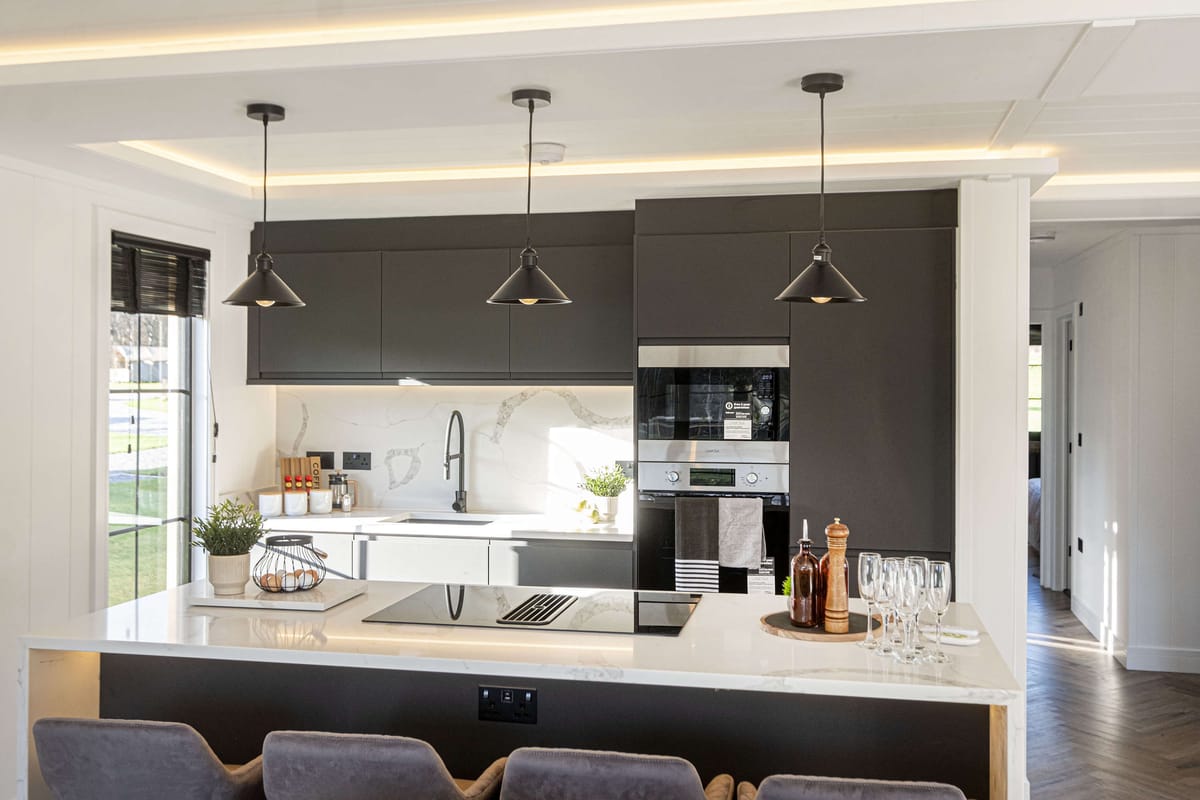 Modern Kitchen with Sleek Black and White Design Featuring Pendant Lighting, Built-in Appliances, Marble Countertops, and Elegant Dining Setup with Wine Glasses and Wooden Accents
