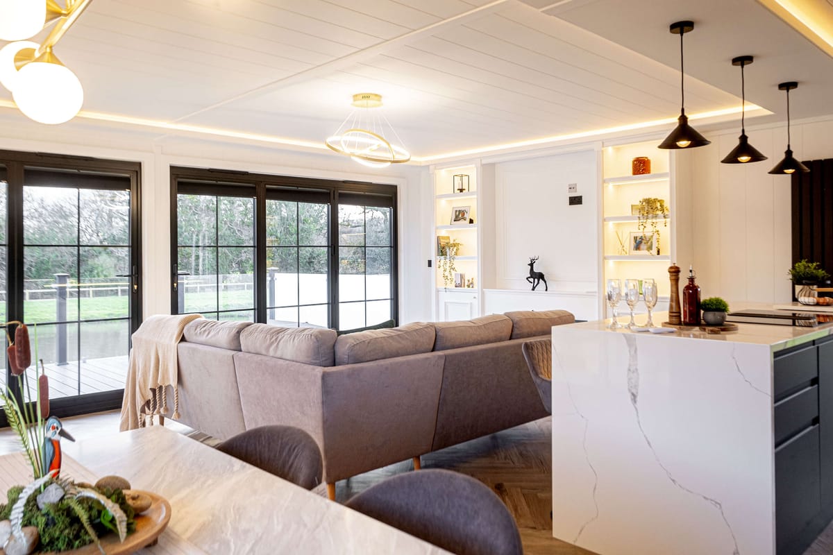 Modern Open-Plan Living Room with Large Windows, Cozy Sectional Sofa, and Stylish Kitchen Island Featuring Minimalist Decor and Warm Lighting