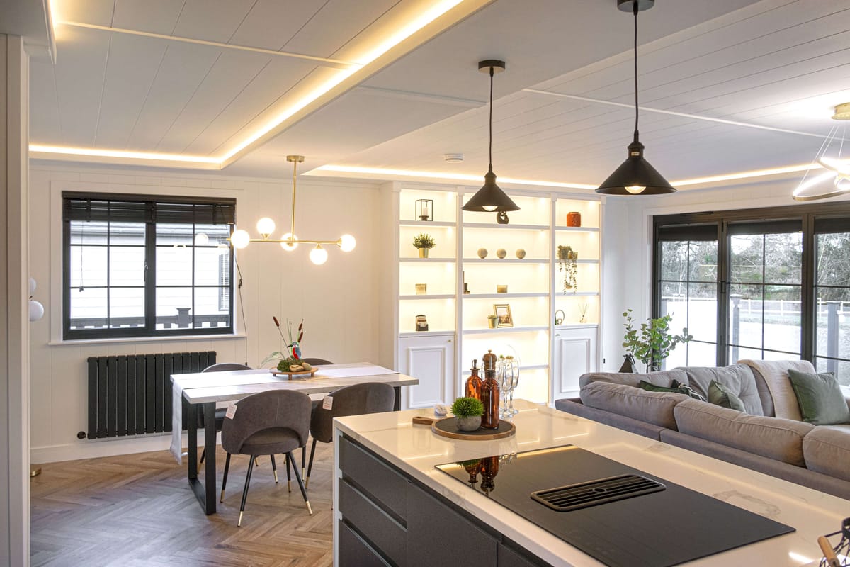 Open-plan living space with a kitchen island, dining area, shelving and large windows