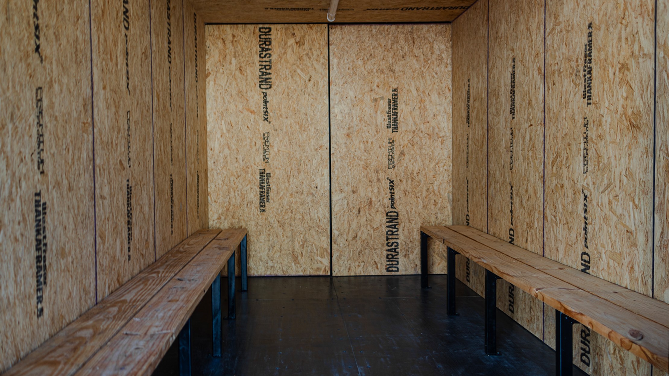 Inside view of a custom cool-down container with durable OSB wall panels and dual wooden benches—designed for onsite worker rest, hydration, and heat-recovery environments.