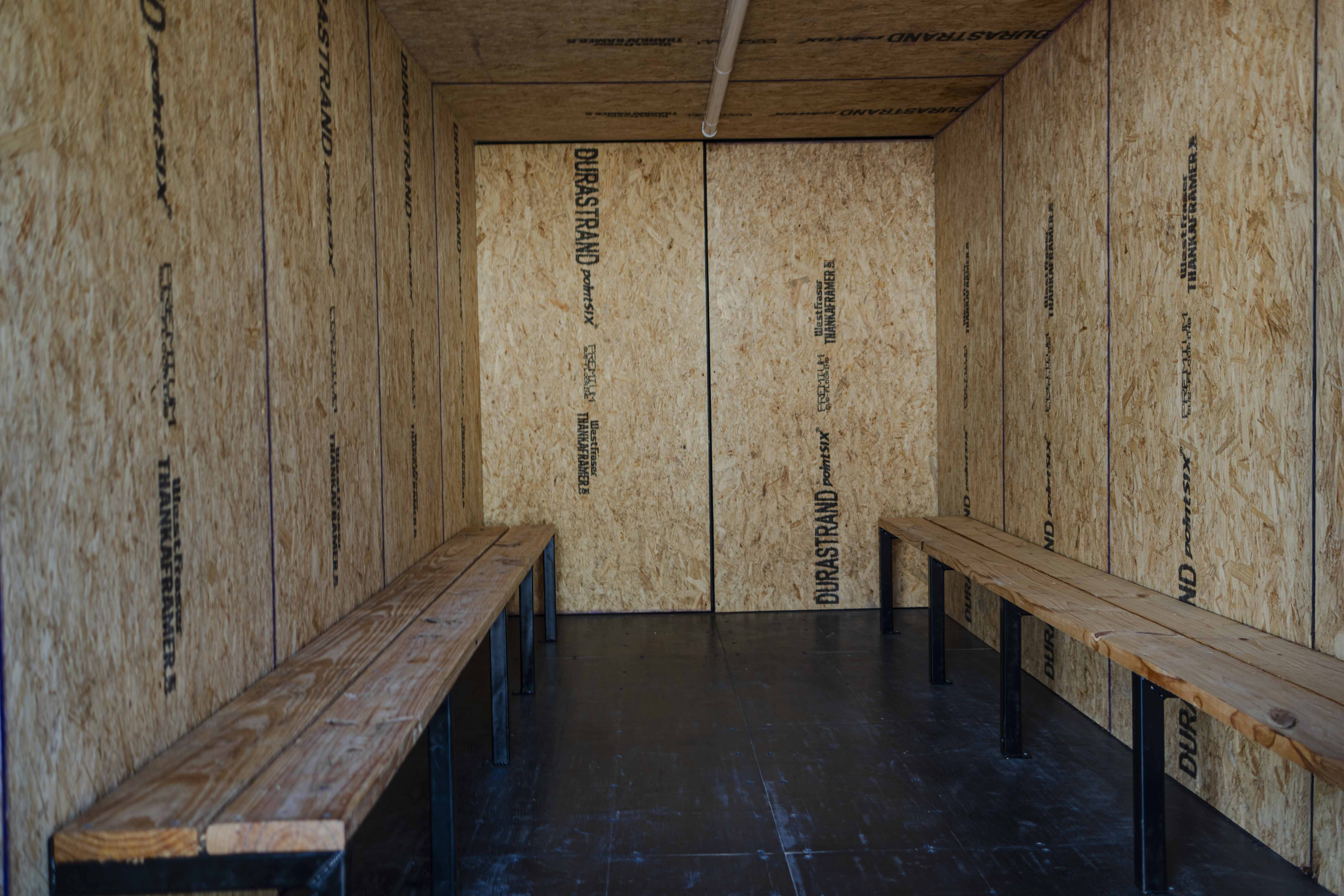 Inside view of a custom cool-down container with durable OSB wall panels and dual wooden benches—designed for onsite worker rest, hydration, and heat-recovery environments.