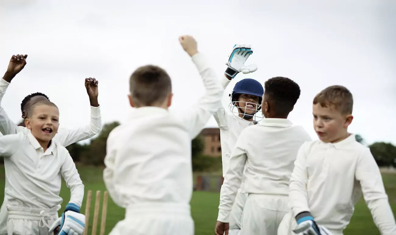 A group of young boys celebrating in a cricket game.